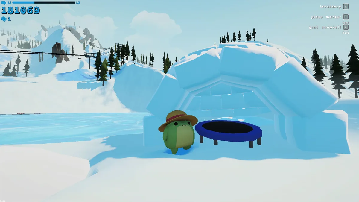 The original green frog beside a blue trampoline placed inside the fishing igloo.